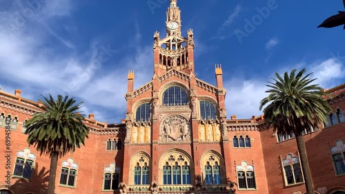 Entrance to Sant Pau Hospital, a masterpiece of Modernism architecture in Barcelona. Pan up to spire tower flanked by palm trees. photo
