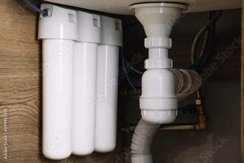 Home water filtration plant close-up. Small water filters under the sink in the kitchen