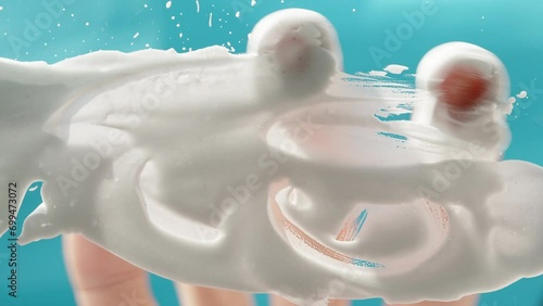 A man spreads white shaving foam across the frame, view from below against a blue background. photo