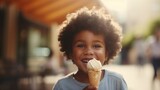 A beautiful cute young black african american baby kid child boy model guy holding and eating a gelato ice cream in a cone outside in a city on a sunny summer day. blurred background