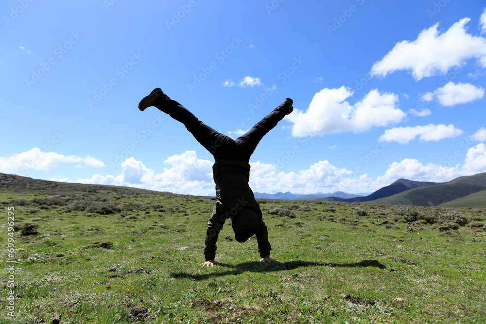 Woman hiker doing a handstand on high altitude mountain meadow Woman hiker doing a handstand on high altitude mountain meadow