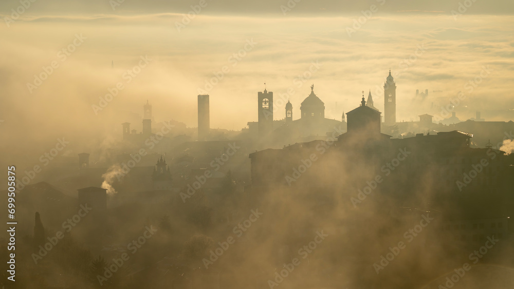 Bergamo, Italy. Amazing aerial landscape of the fog rises from the plains and covers the old town during sunrise. Warm colors. Bergamo one of the most beautiful city in Italy