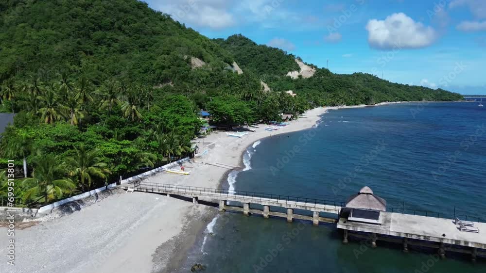 Concrete fishing pier along the beach in a small fishing village. Drone aerial