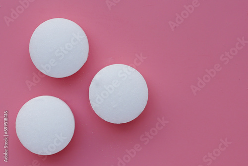 White mothballs on pink background.