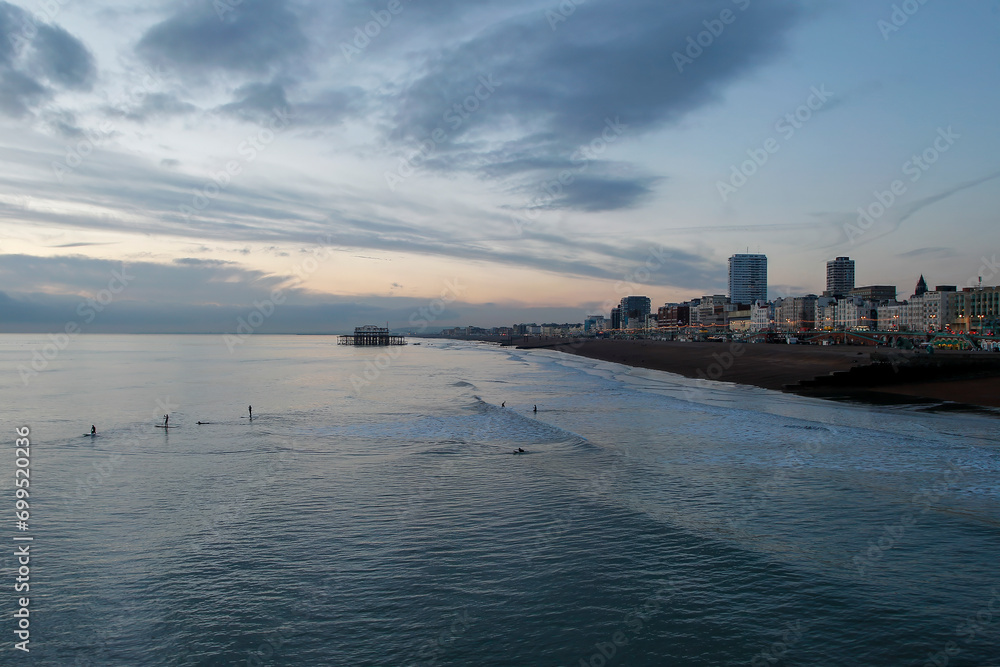 Brighton seafront at sunset with paddle boarders on waves