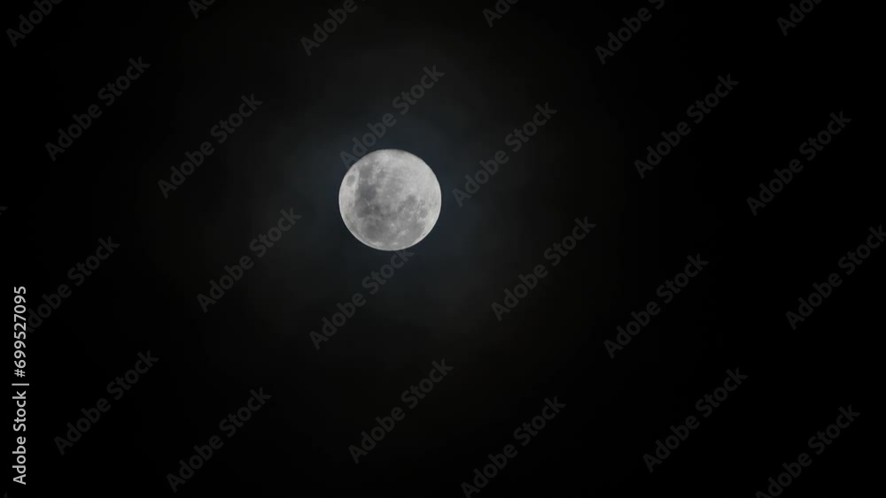 Full moon with moving black clouds. Clouds floating through the bright disk of the moon. Mysterious night scene Full moon with moving black clouds. Clouds floating through the bright disk of the moon. Mysterious night scene