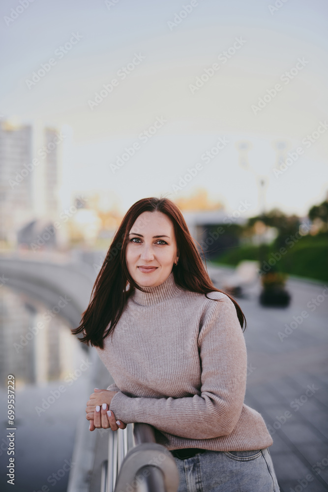 Brunette Caucasian woman portrait in the city, beautiful smiling businesswoman posing on the embankment