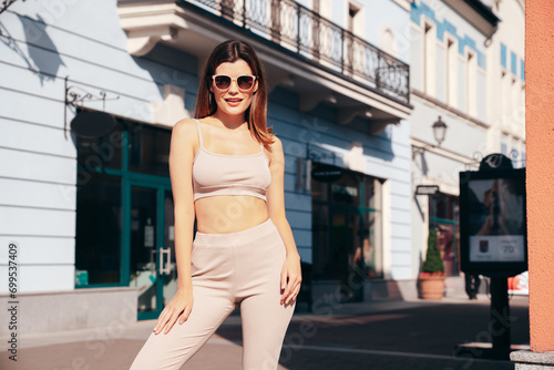 Young beautiful smiling woman in trendy summer clothes. Sexy carefree model posing on the street background at sunset. Positive brunette female. Cheerful and happy. In Europe city. In sunglasses © halayalex