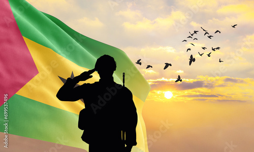 Silhouette of a soldier with the São Tomé and Príncipe flag stands against the background of a sunset or sunrise. Concept of national holidays. Commemoration Day. photo