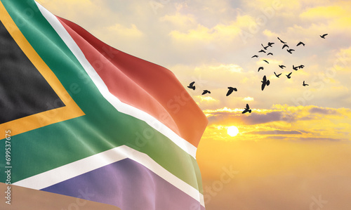 Waving flag of South Africa against the background of a sunset or sunrise. South Africa flag for Independence Day. The symbol of the state on wavy fabric. photo
