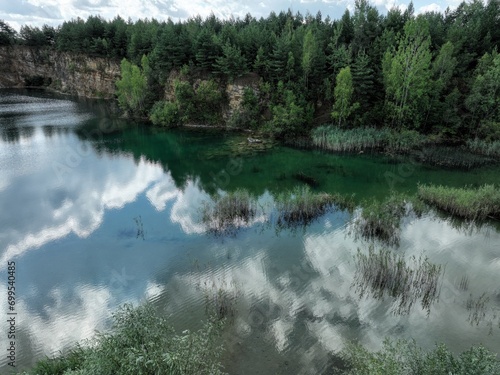 jezioro o przezroczystej wodzie pośród lasu oraz odbijające niebo, ekologiczny ekosystem, czyste powietrze, czysta woda, świeże powietrze, las oraz woda 