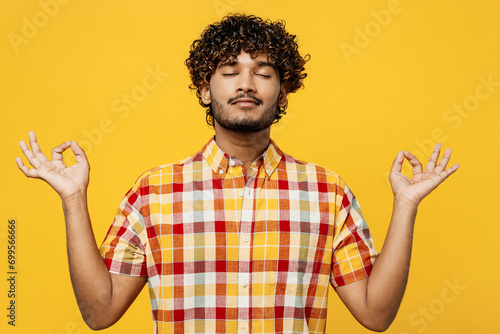 Young spiritual Indian man he wear shirt casual clothes hold spreading hands in yoga om aum gesture relax meditate try to calm down isolated on plain yellow color background studio. Lifestyle concept