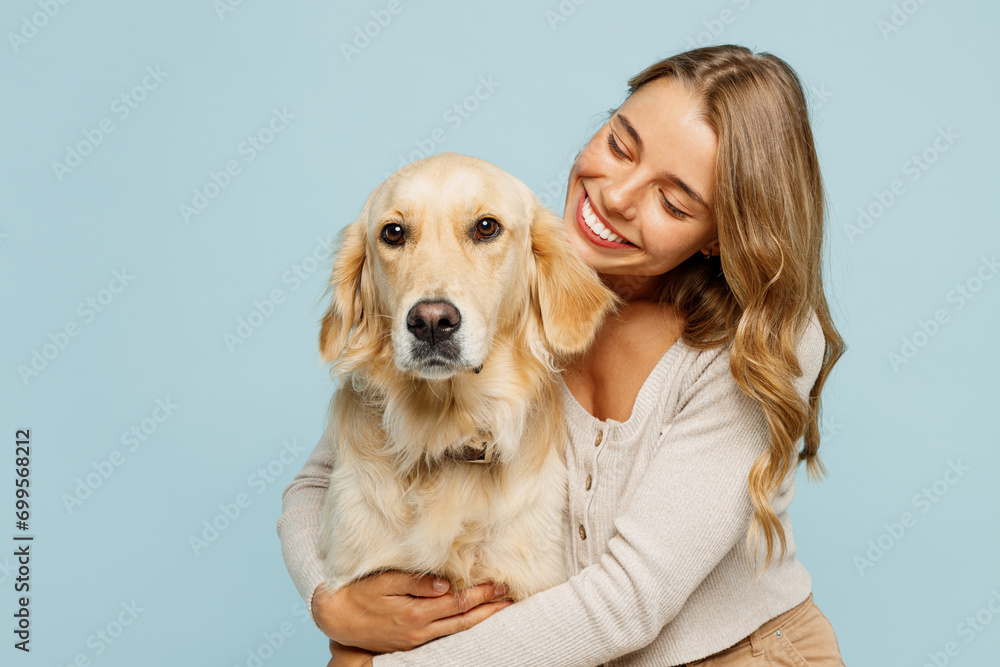 Young smiling happy cheerful owner woman with her best friend retriever wear casual clothes cuddle hug look at dog isolated on plain pastel light blue background studio. Take care about pet concept.