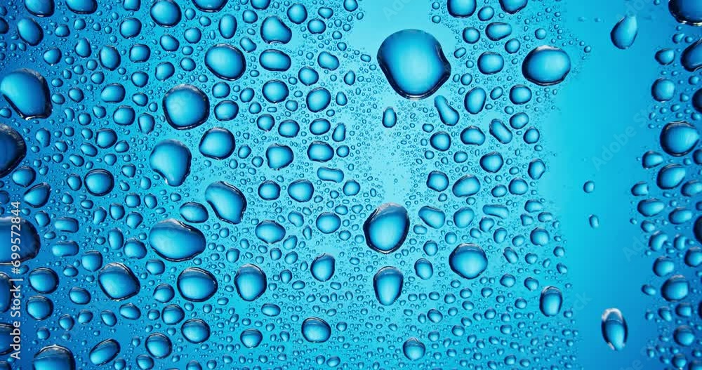 Water droplets falling down the glass surface