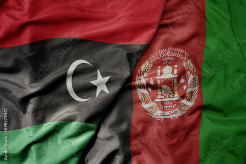big waving national colorful flag of afghanistan and national flag of libya .