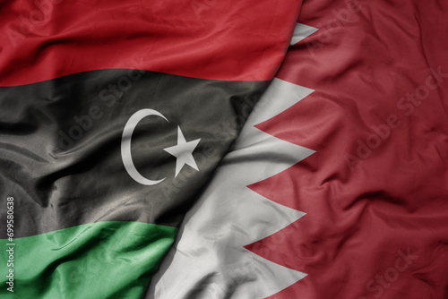 big waving national colorful flag of bahrain and national flag of libya .
