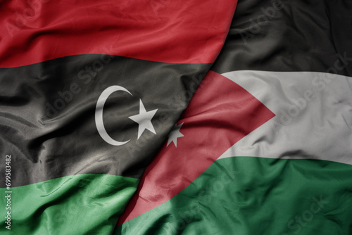 big waving national colorful flag of jordan and national flag of libya .