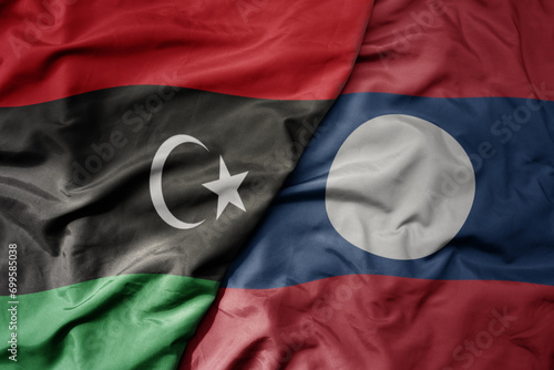 big waving national colorful flag of laos and national flag of libya .