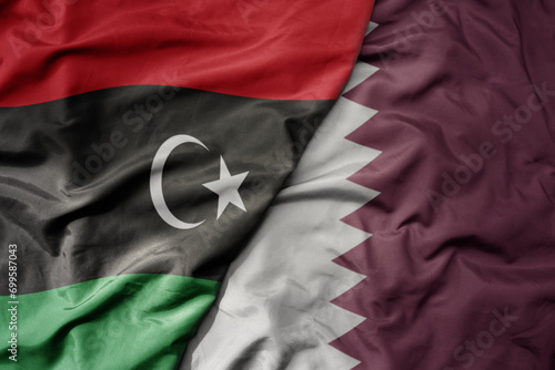 big waving national colorful flag of qatar and national flag of libya .