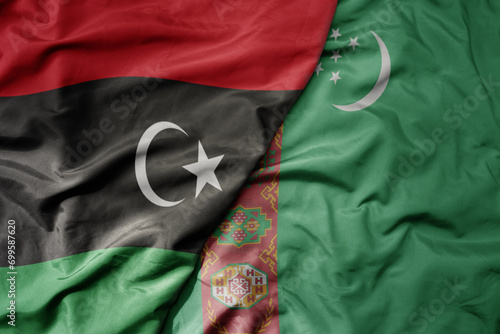 big waving national colorful flag of turkmenistan and national flag of libya .