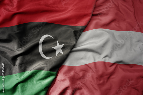 big waving national colorful flag of austria and national flag of libya .