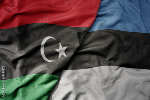 big waving national colorful flag of estonia and national flag of libya .