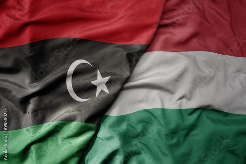 big waving national colorful flag of hungary and national flag of libya .