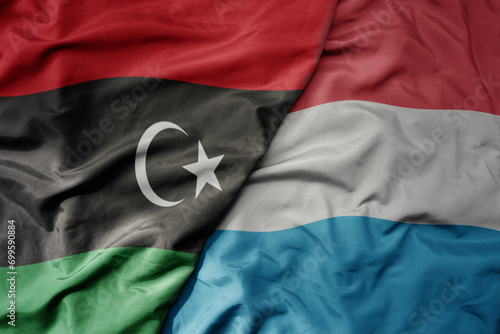 big waving national colorful flag of luxembourg and national flag of libya .