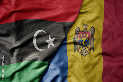 big waving national colorful flag of moldova and national flag of libya .