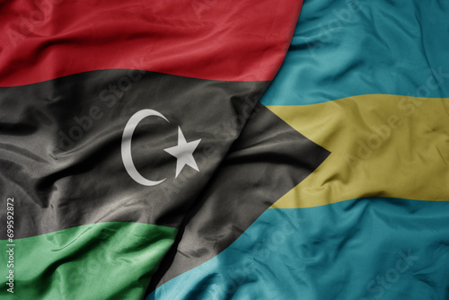 big waving national colorful flag of bahamas and national flag of libya .