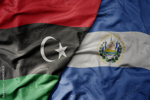 big waving national colorful flag of el salvador and national flag of libya .