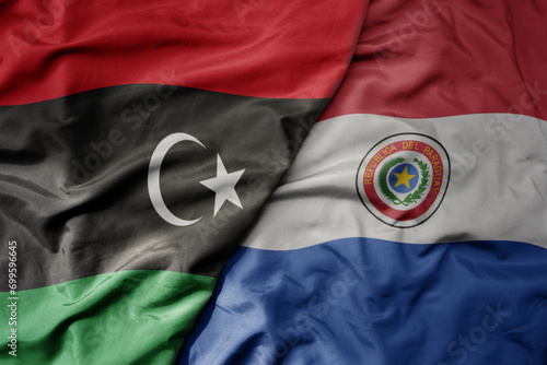 big waving national colorful flag of paraguay and national flag of libya .