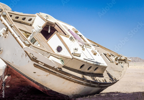 old yacht lies on the sand in the desert against the blue sky in Egypt Dahab South Sinai