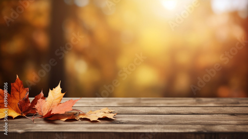 Wooden table with brown leaves and blurred autumn background.