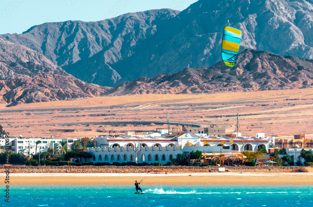 Obraz premium one surfer with a sail on a rocky shore and hotels in the Red Sea in Egypt