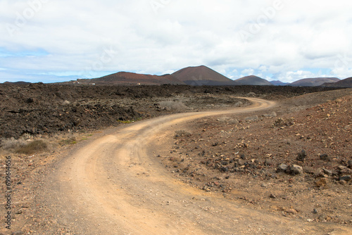 Country road in a volcanic landscape in Los Ajaches National Park near Papagayo. Playa Blanca, Lanzarote, Spain. Tourism and vacations concept. 
