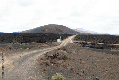 Country road in a volcanic landscape in Los Ajaches National Park near Papagayo. Playa Blanca, Lanzarote, Spain. Tourism and vacations concept. 