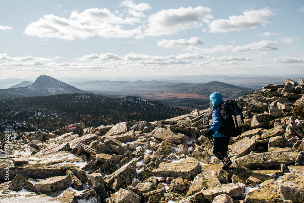 a girl with backpacks walks on rocks in the snow a girl with backpacks walks on rocks in the snow