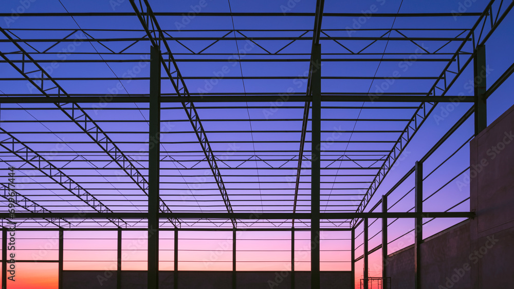 Obraz premium Silhouette of metal roof beam and column of industrial factory building outline structure in construction area against colorful twilight sky background