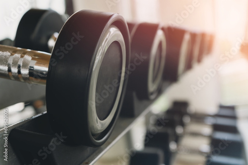 Exercise equipment or dumbbells, which are used to exercise muscles, are placed on shelves inside the gym, with sunlight streaming in through the windows.