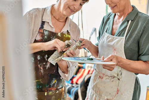 smiling mature women mixing paints on color palette during painting master class in art studio