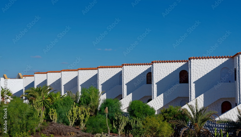 Häuserzeile in traditioneller Bauweise mit grünem Garten und blauem Himmel