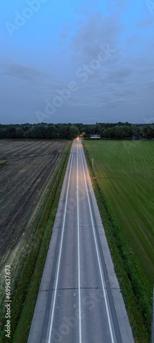 Fotografie This vertical image showcases a country road taken at twilight, captured from an aerial view