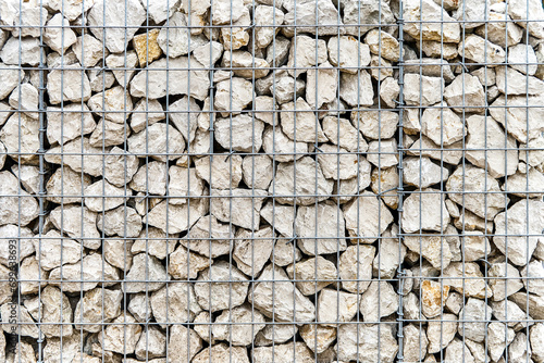 Traditional gabion wall made of rocks and metal grid as background. Stone wall with steel mesh as landscaping element. Building fence detail photo