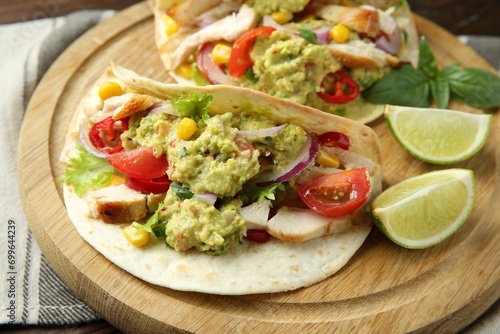 Delicious tacos with guacamole, meat and vegetables served with lime on table, closeup