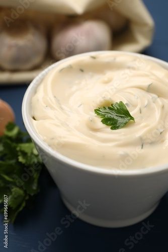 Tasty garlic sauce with parsley on blue table, closeup