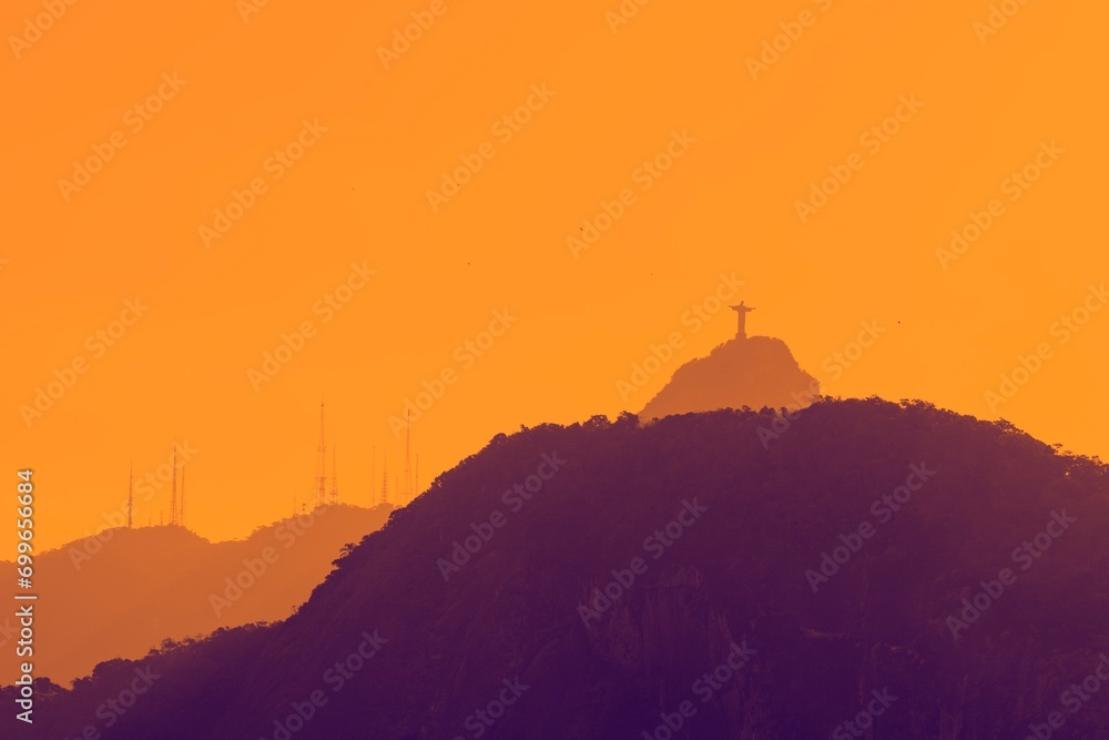 Rio de janeiro, Brazil. Silhouette of natural mountain landscape with statue of Jesus and TV and radio antennas during sunset.