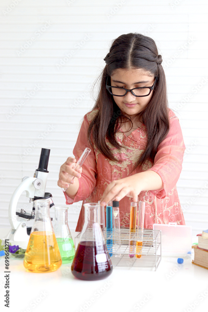 Cute Indian school girl in India traditional dress costume doing science experiments in laboratory, young scientist kid with microscope and lab equipment learning biologics and chemistry in classroom. Cute Indian school girl in India traditional dress costume doing science experiments in laboratory, young scientist kid with microscope and lab equipment learning biologics and chemistry in classroom.