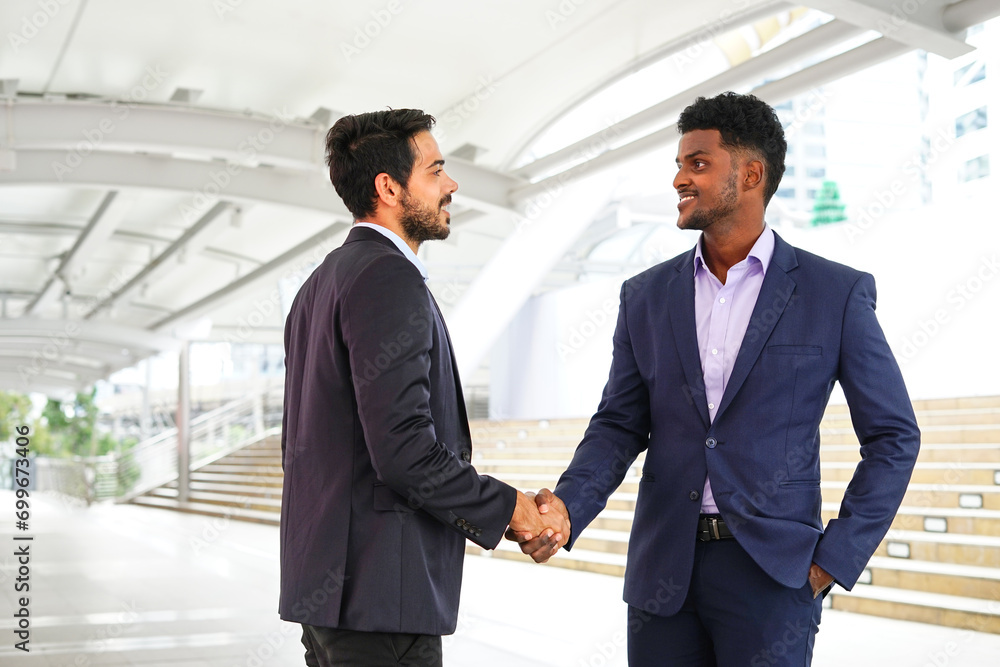 two businessmen shaking hands to greet each other outside office two businessmen shaking hands to greet each other outside office