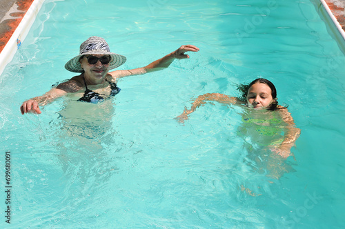 avó e neta brincando juntas em água de piscina  photo